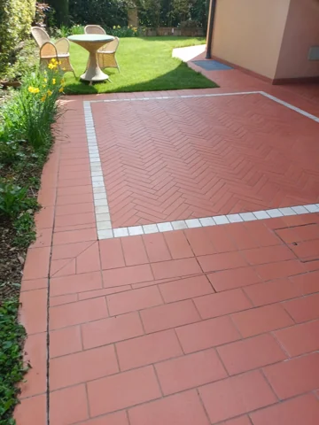 Pavimentazione esterna in cotto accanto a un giardino